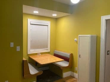 Cozy dining nook with yellow walls, a wooden table, and retro-style benches.