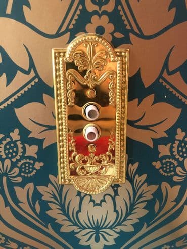Elegant gold wall switchplate against a floral patterned background.