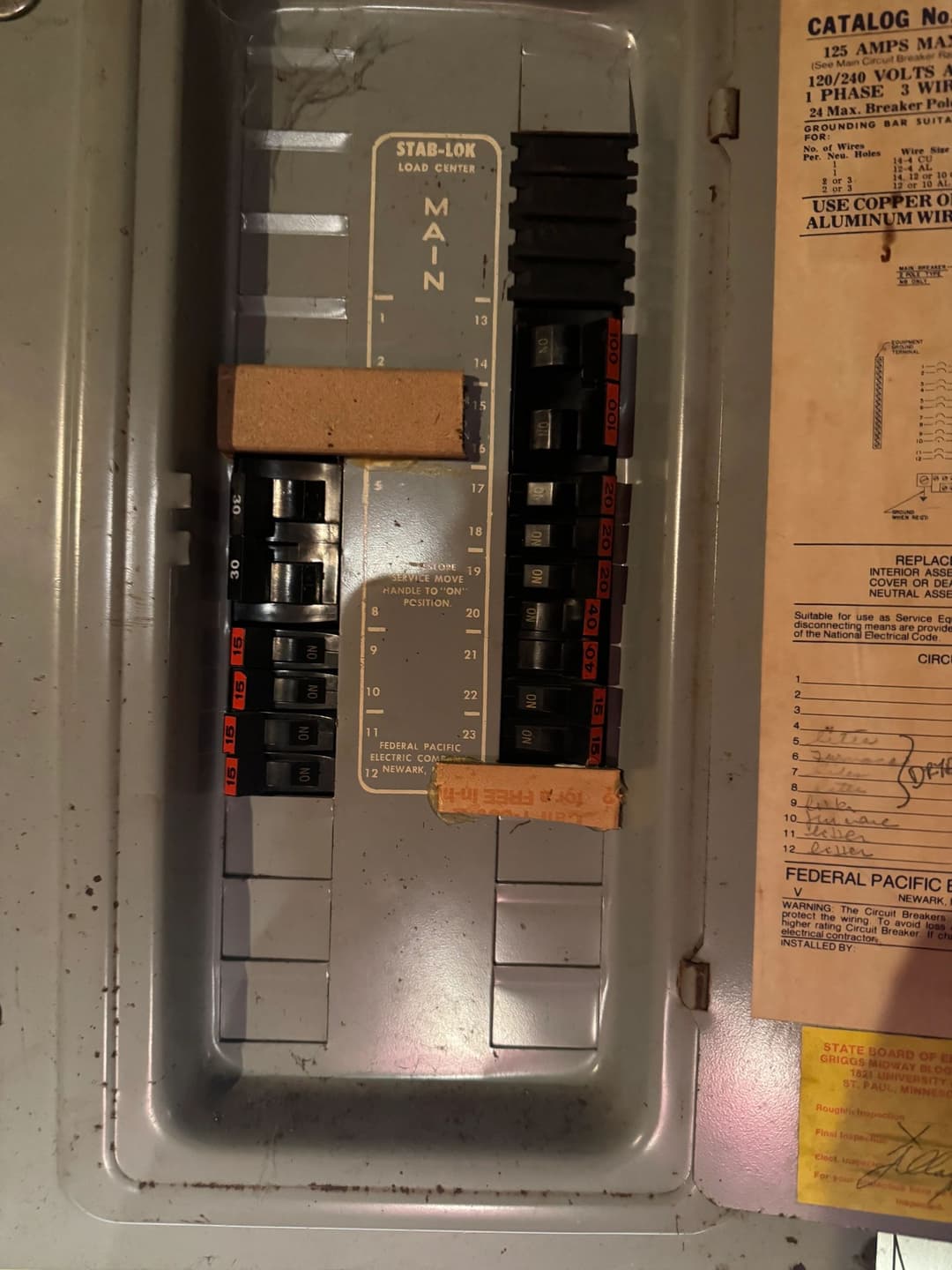 Circuit breaker panel with labeled switches and safety warnings for electrical appliances.